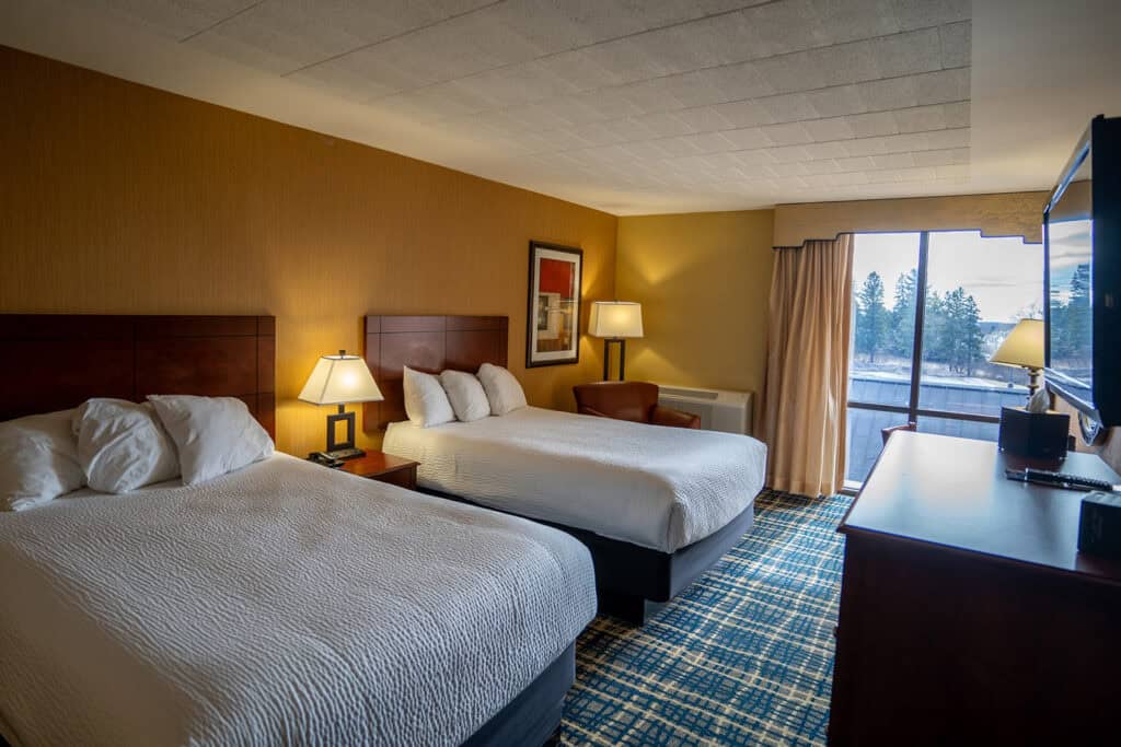 Modern Odawa Casino & Resort hotel room with comfortable beds, warm lighting, and scenic view.