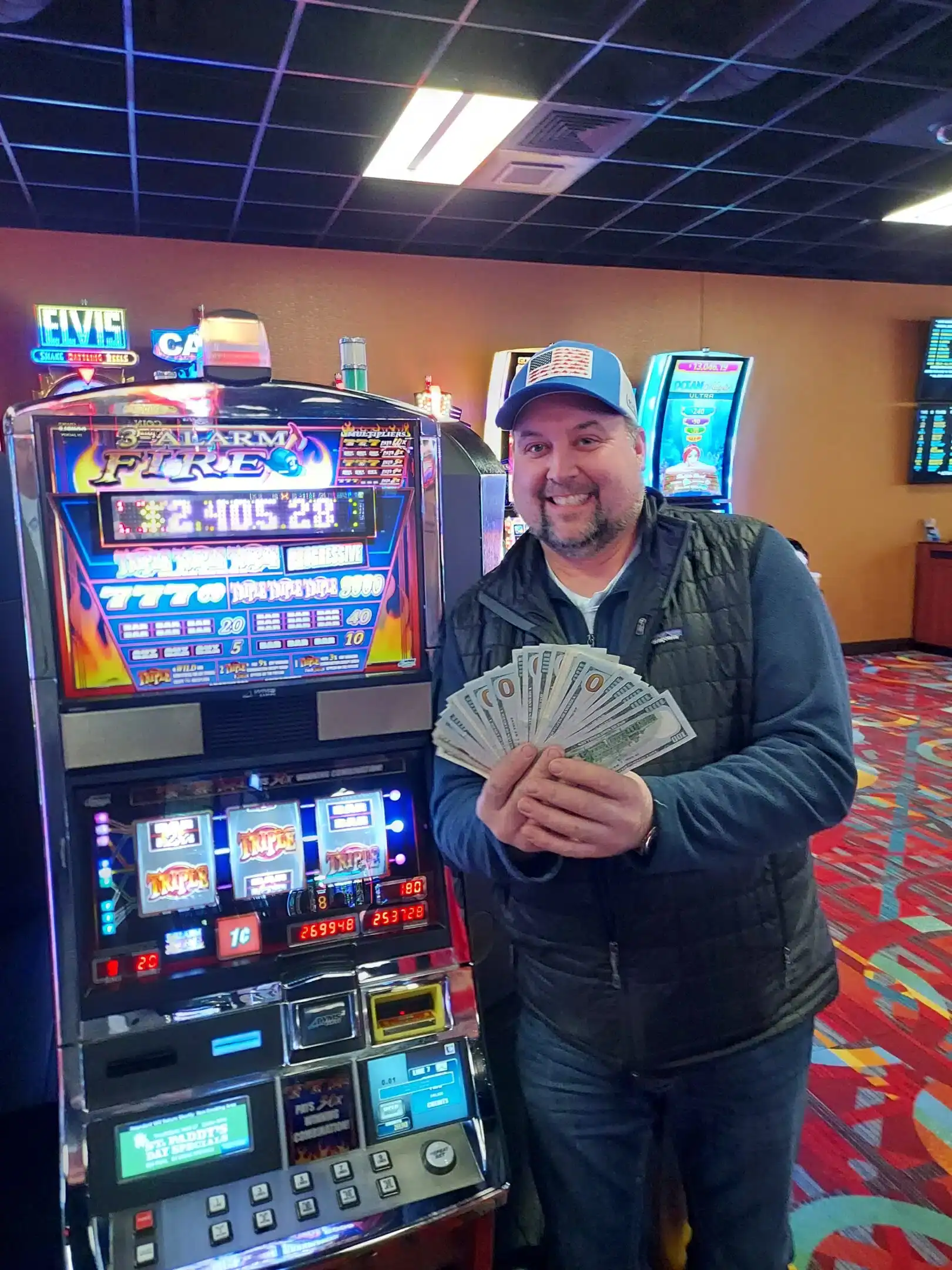 Winnings at Odawa Casino & Resort, man holding cash next to slot machine, vibrant casino gaming environment in Michigan.