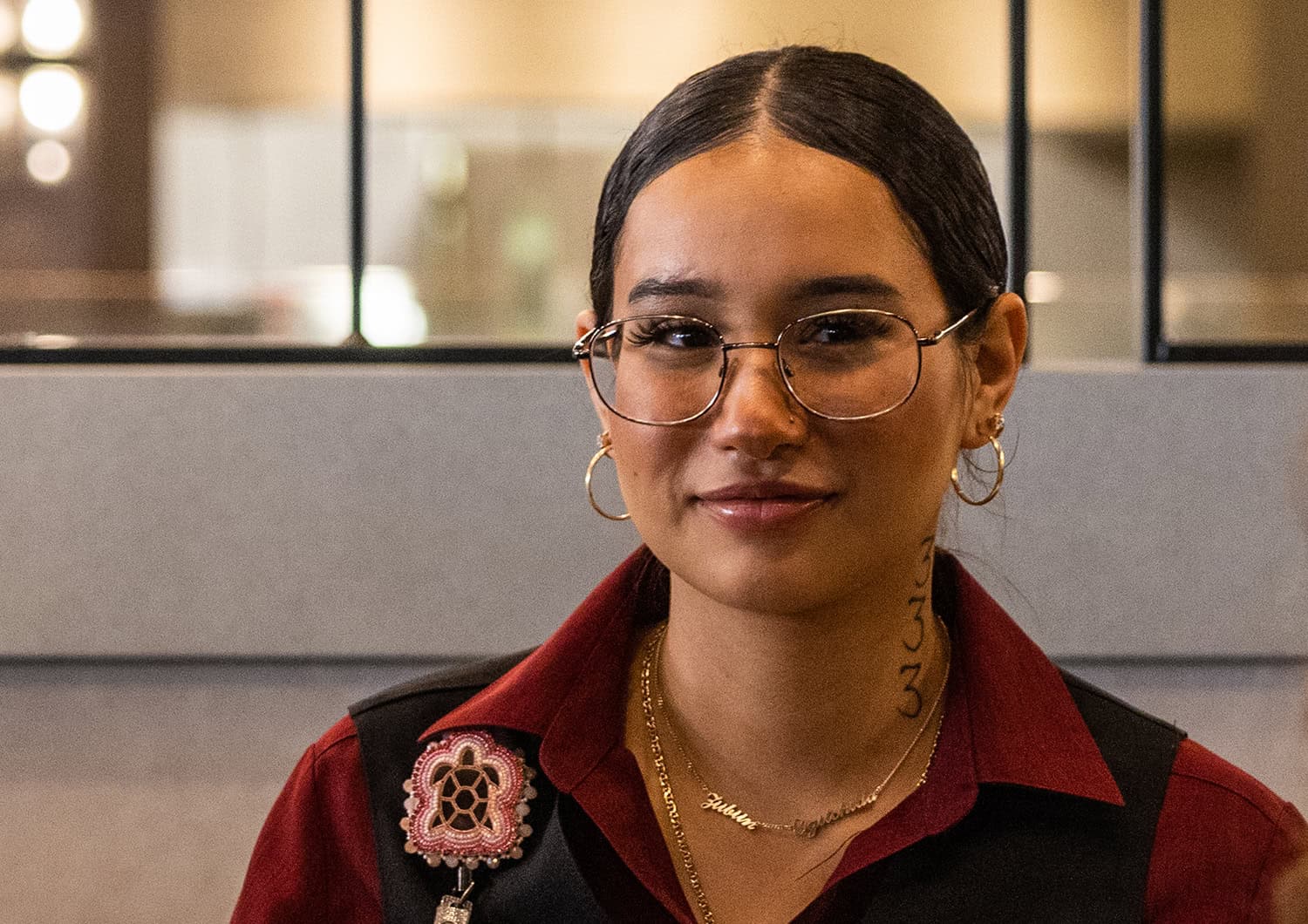 Friendly young woman with glasses at Odawa Casino & Resort, smiling in vibrant attire celebrating Native American hospitality.