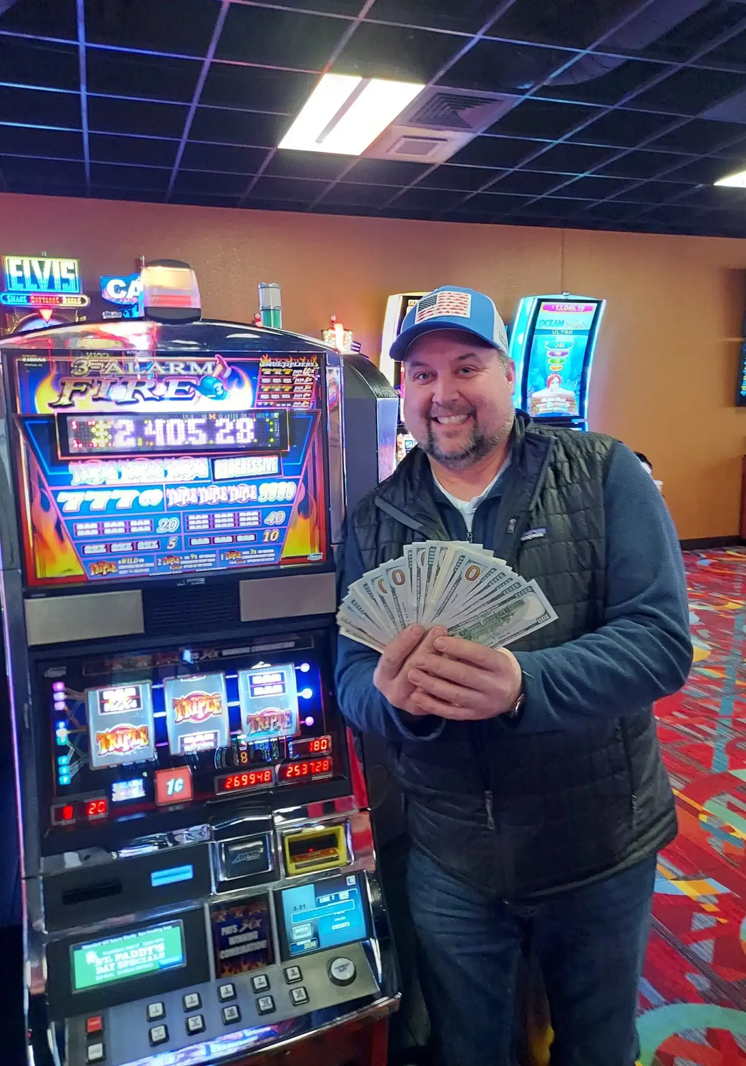 Winnings at Odawa Casino & Resort, man holding cash next to slot machine, vibrant casino gaming environment in Michigan.
