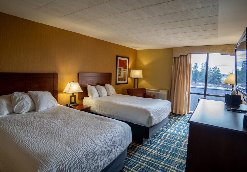 Modern Odawa Casino & Resort hotel room with comfortable beds, warm lighting, and scenic view.