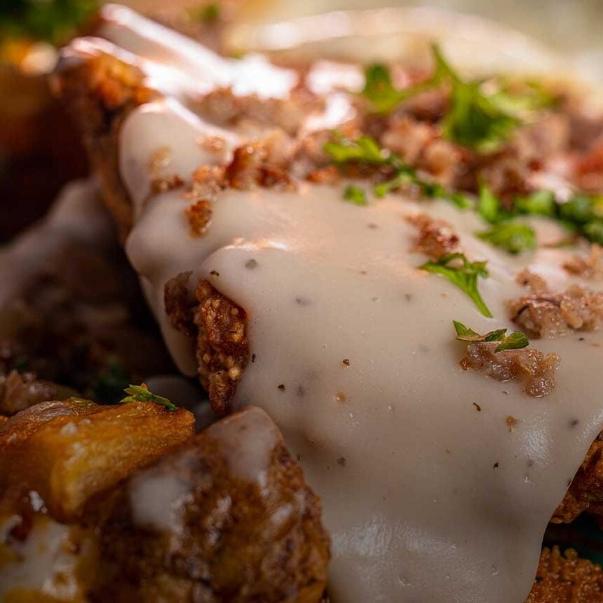 Crispy chicken with white gravy and herbs, comfort food dish.