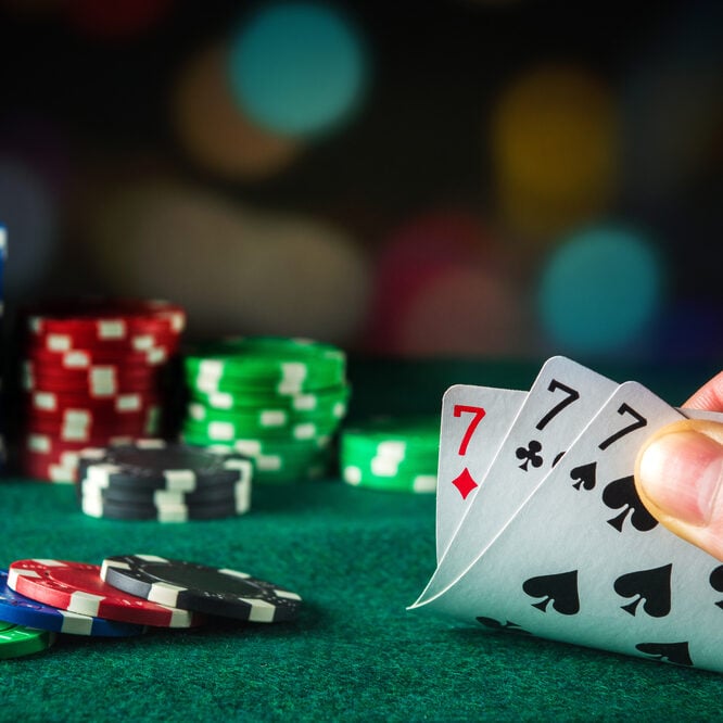 Colorful poker chips and playing cards on a green casino table.