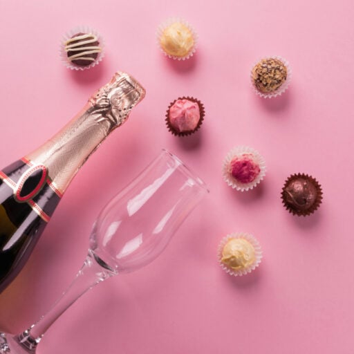 Festive champagne bottle with colorful chocolates on pink background, ideal for celebration at Odawa Casino & Resort.