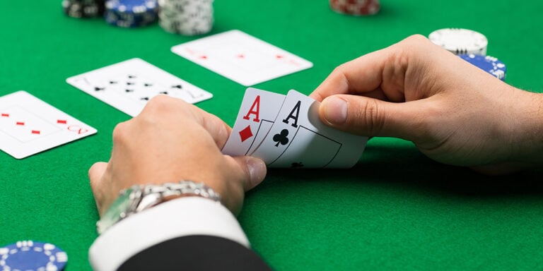 Ace of diamonds and clubs playing cards with poker chips on a green blackjack table at Odawa Casino & Resort.